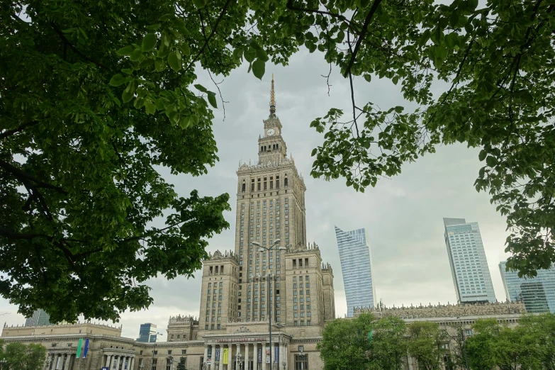 the building with its spire is shown through trees