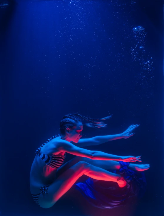 a girl is floating underneath water and reaching out for soing