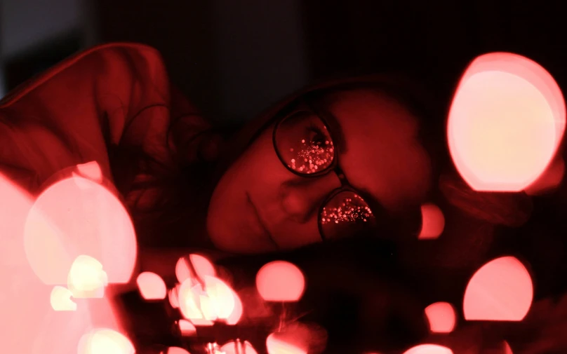 young woman laying down with glasses on her face