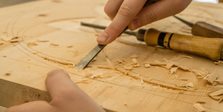 a person is carving a piece of wood with a large knife