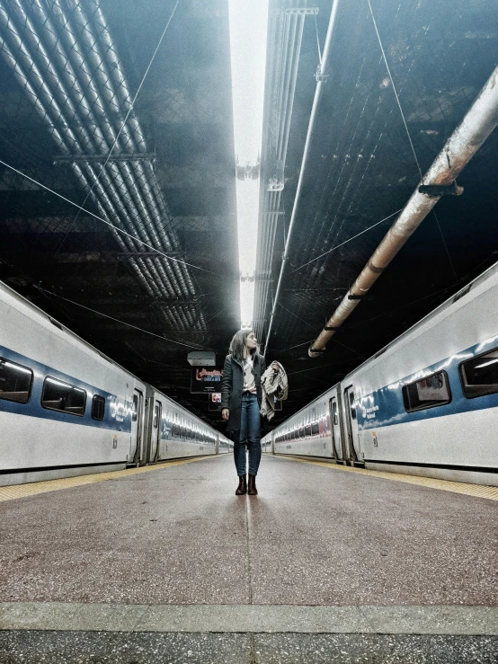 a man is standing on the platform by two trains