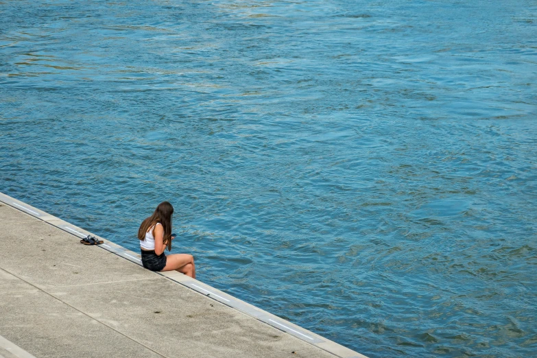 two women sitting on steps next to a body of water