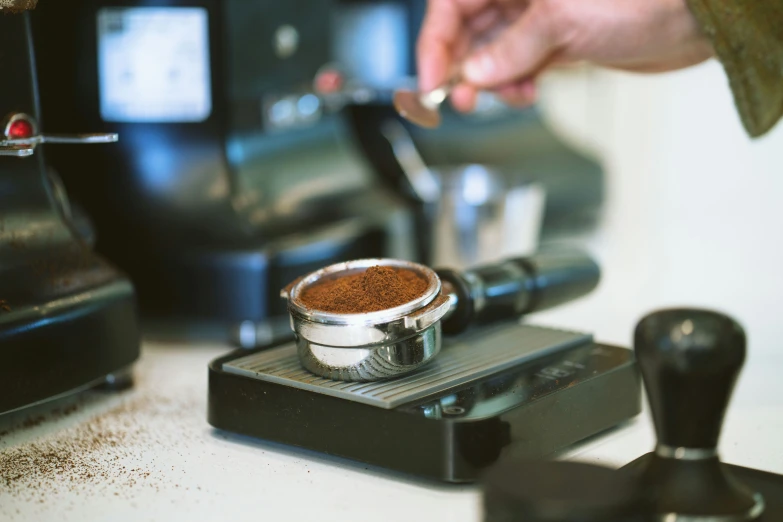 a person is taking some coffee from a grinder