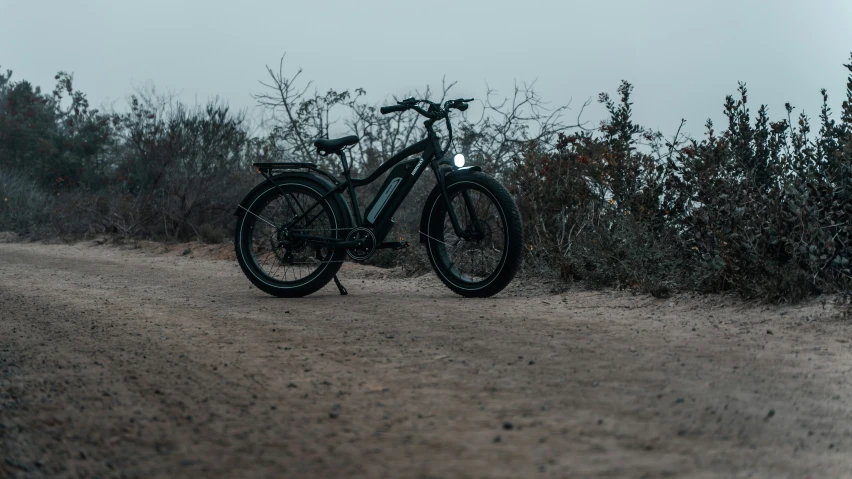 a bike parked on the side of a dirt road