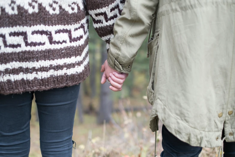 two people holding hands in a forest