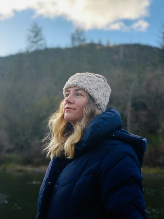 a woman stands near the edge of a lake