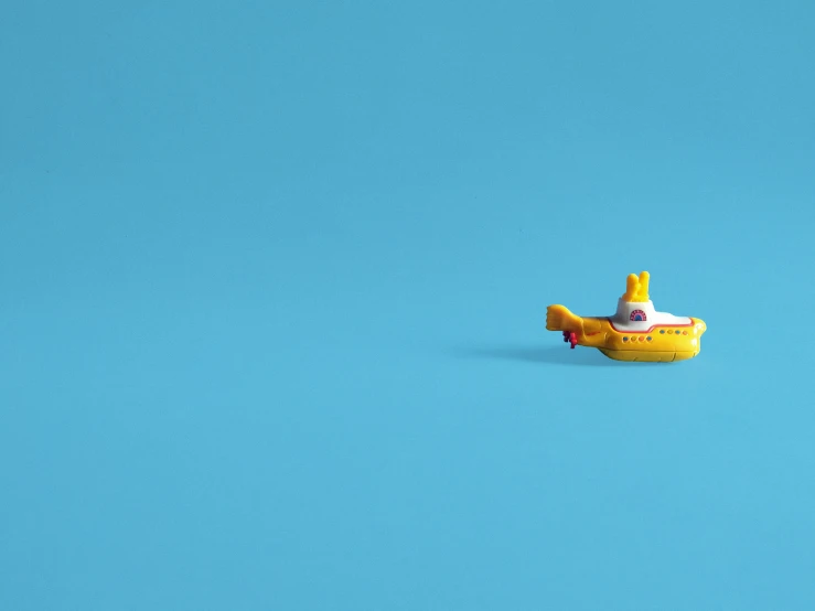 a yellow toy boat floating on top of a blue surface