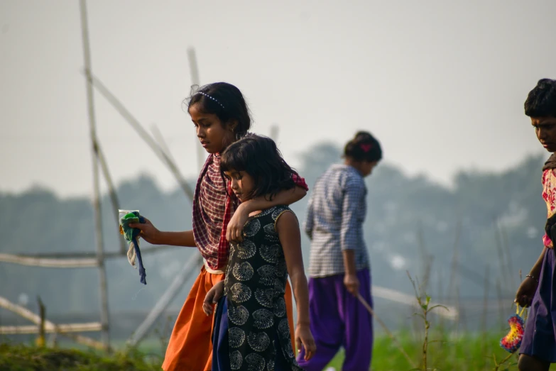 three children with different outfits standing in a field