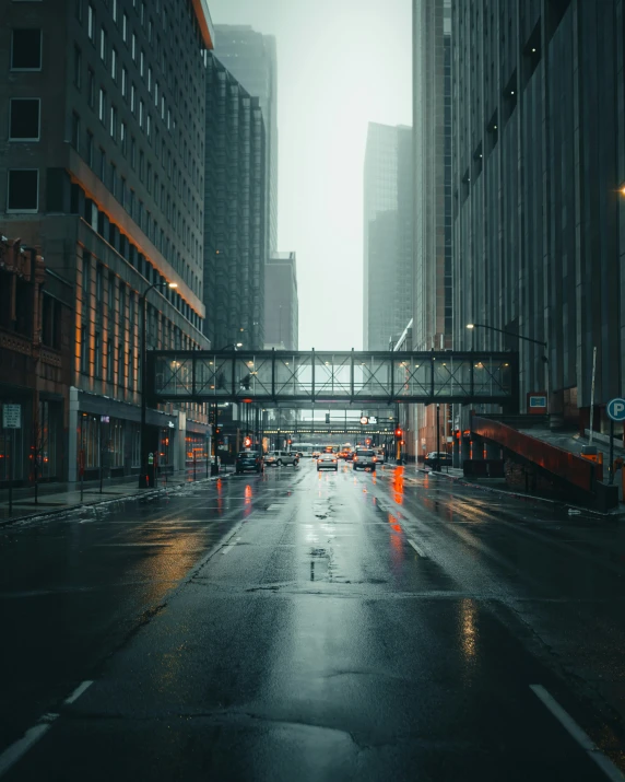 a rain covered street with multiple lanes of roadway with traffic