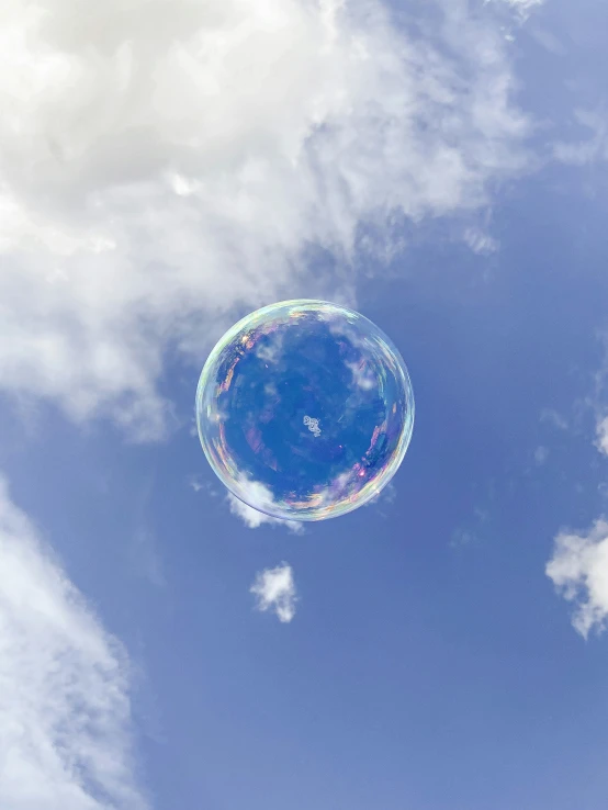 a large bubble flying through the air next to clouds