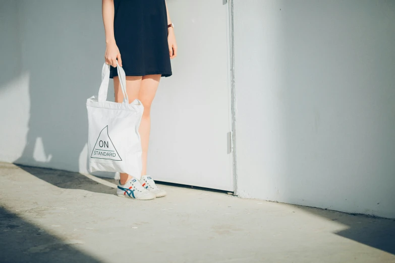 a woman standing next to a door holding a tote bag