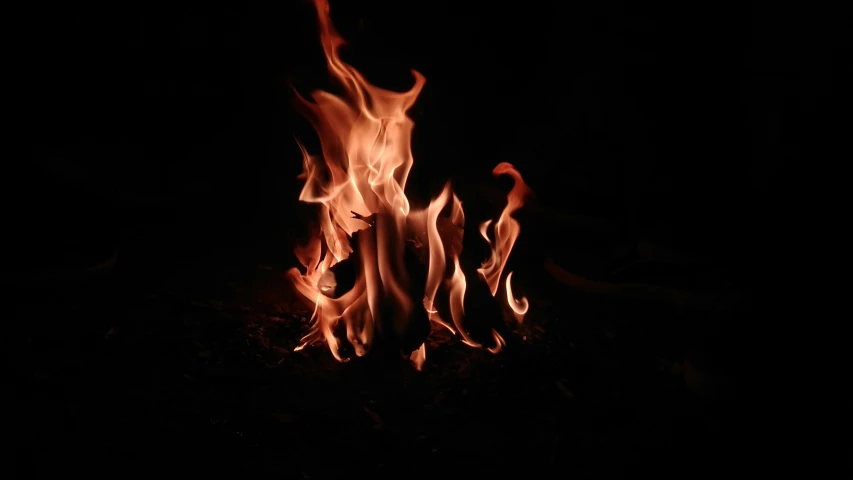 a large fire burns in the dark on a black background