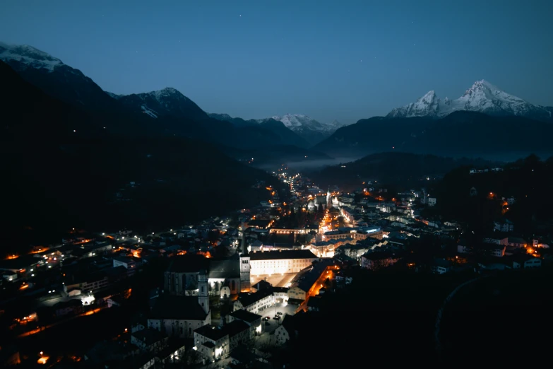 a town at night next to mountains with street lights