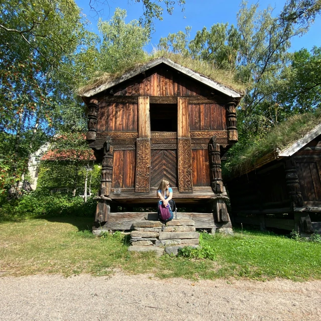 a woman sitting on a stone steps outside of a wooden building