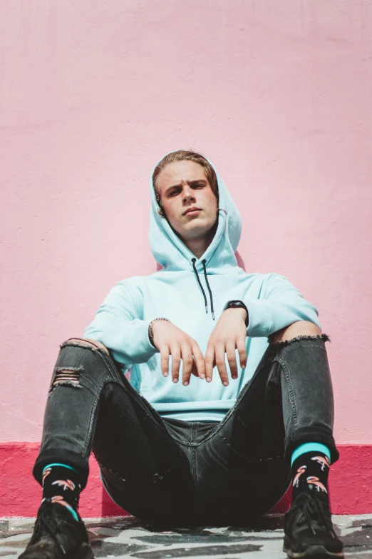 a male in a blue hoodie sitting on the ground