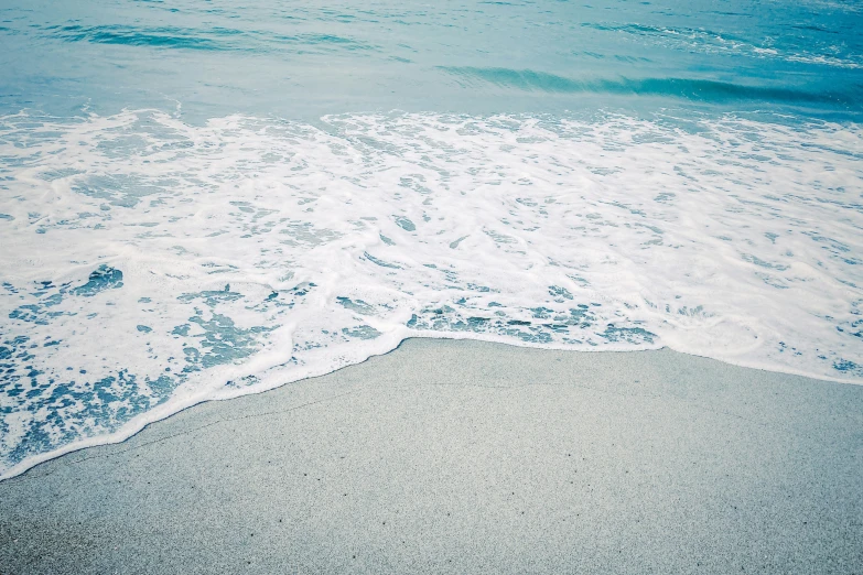 a sandy beach with blue and white waves crashing