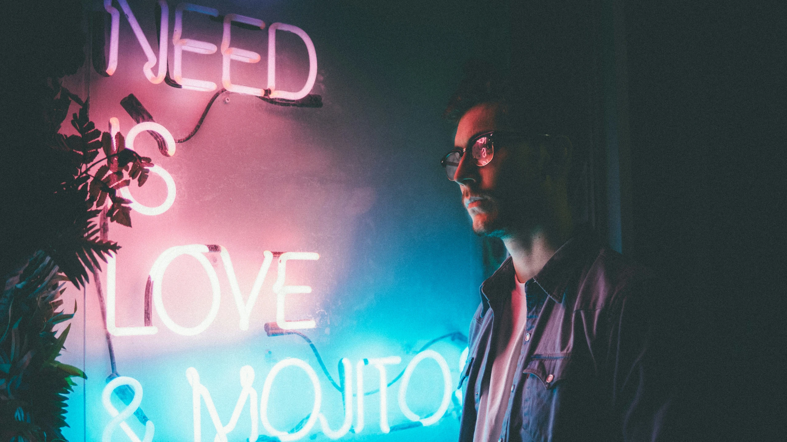 man standing in front of neon sign on wall reading love & moto