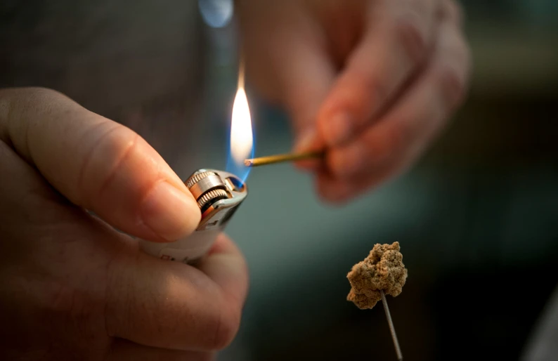 two people lighting cigarettes with small cigarettes in the background