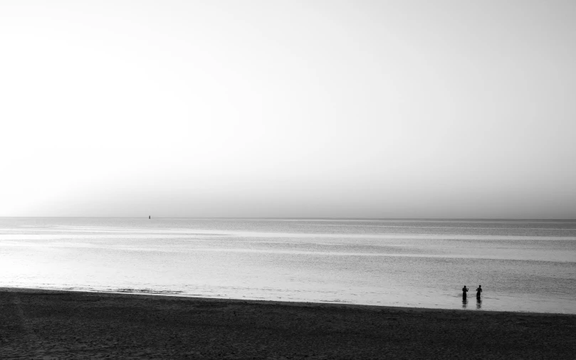 two people walk on the beach with one holding an umbrella