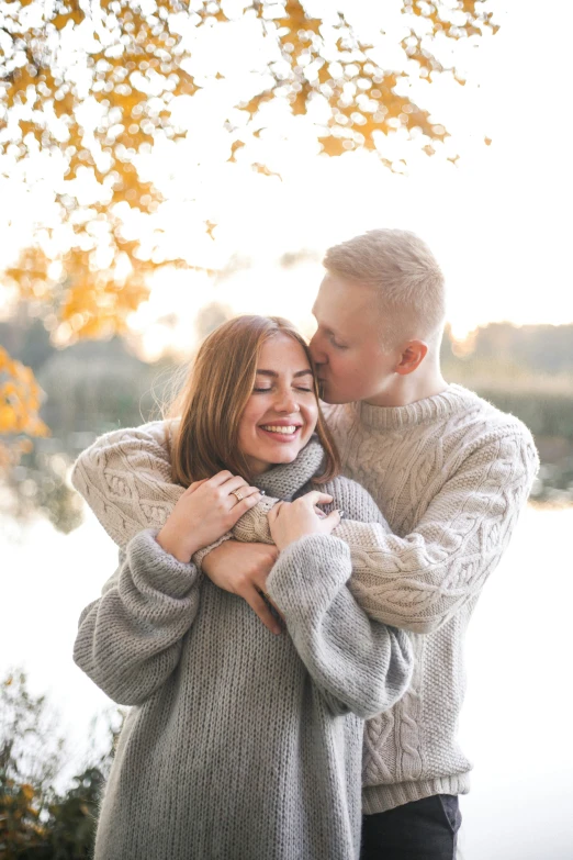 two people sharing a hug near a pond