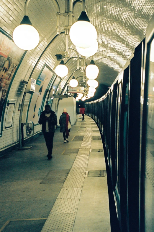 people are walking along the railway platform