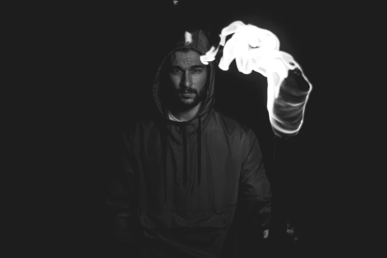 a man is smoking in the dark with one hand and holding a cigarette in the other