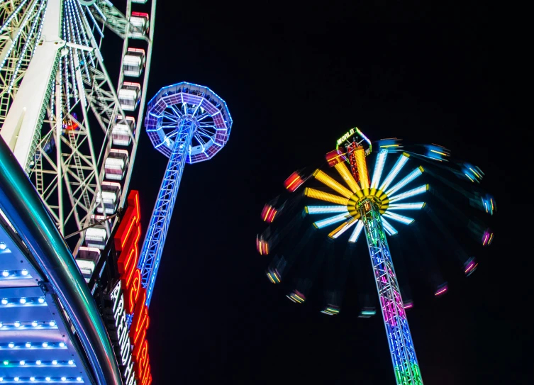 some ferris wheels and other rides on a dark sky