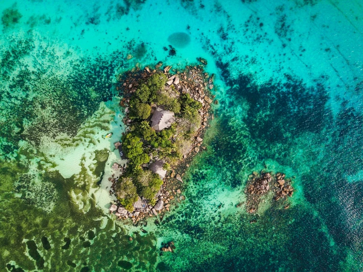 an aerial view of some small rocks in the middle of a body of water