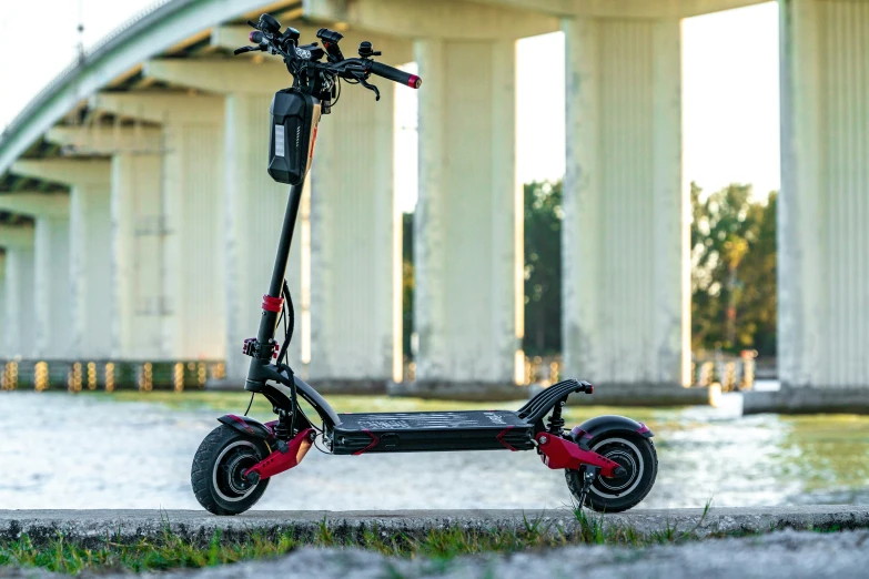 a scooter stands by the water underneath an overpass