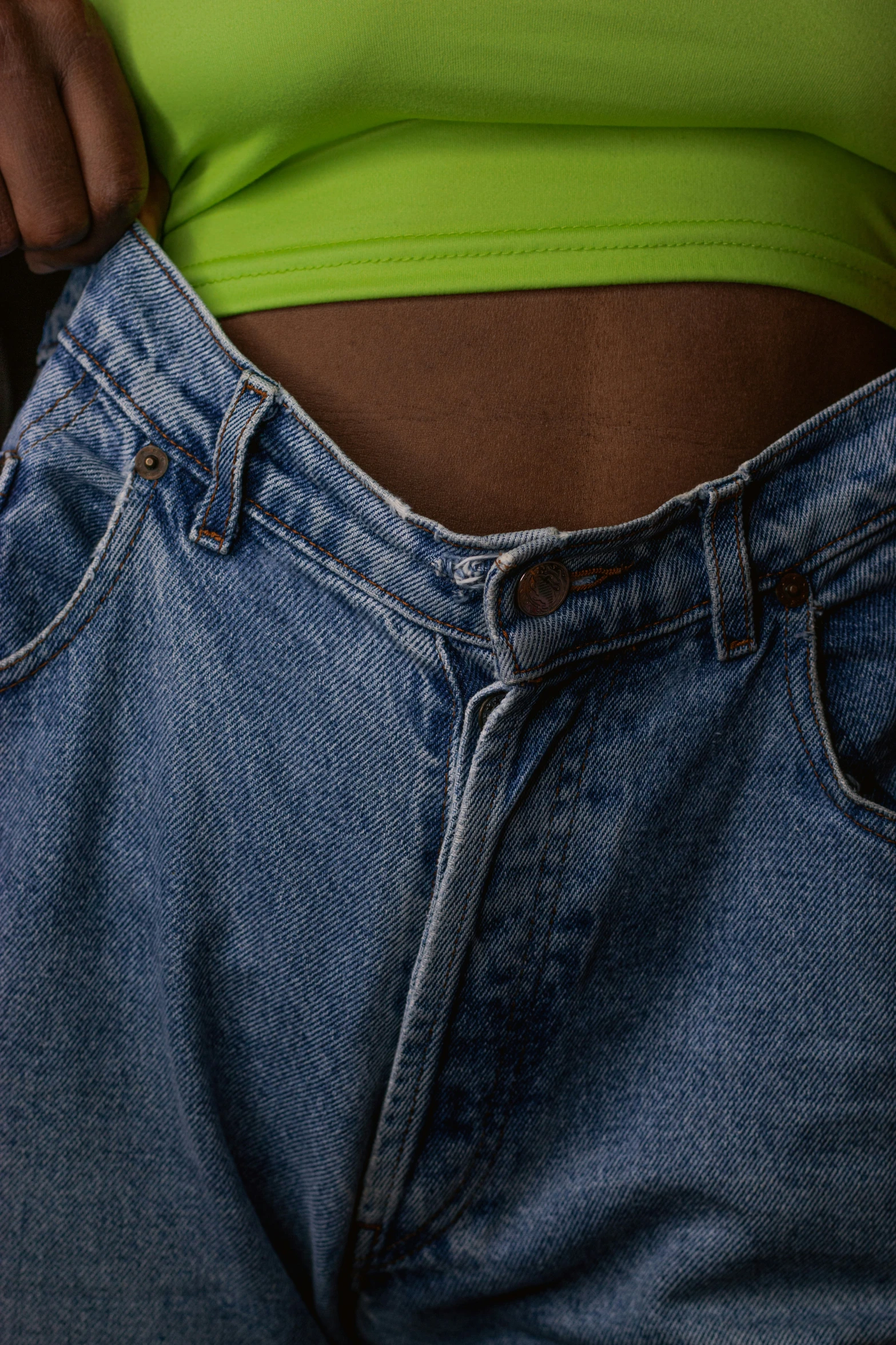 the lower portion of a woman's jeans showing her navel piercings