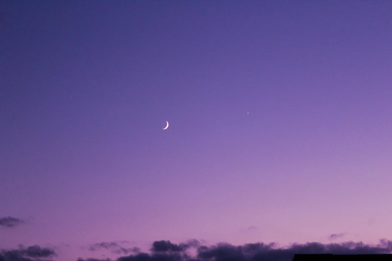 a purple and blue cloudy sky with a partial moon