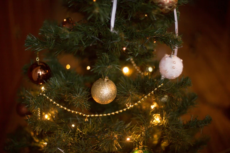 a lit christmas tree with ornaments hanging on it