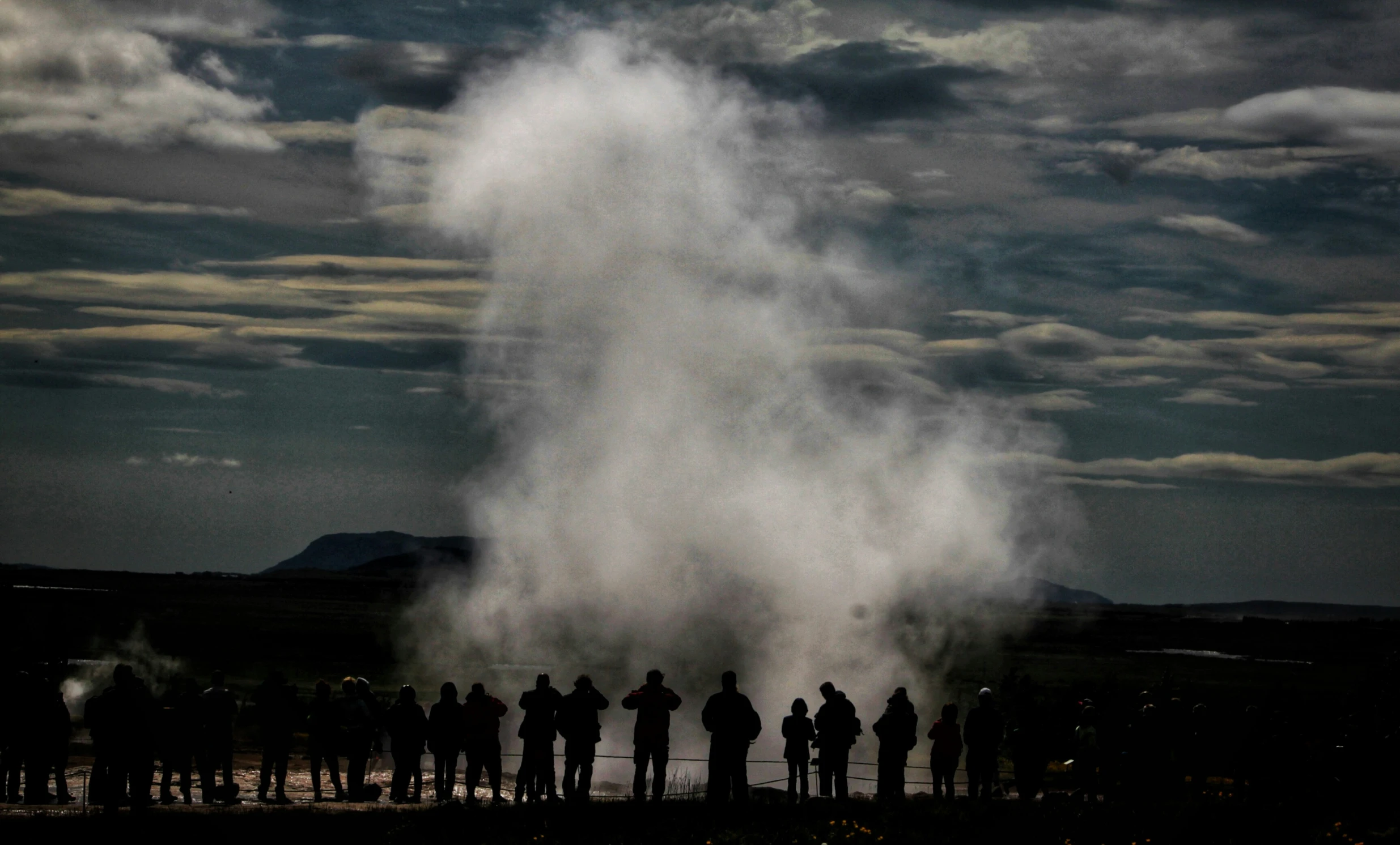 a group of people that are looking at steam coming from the ground