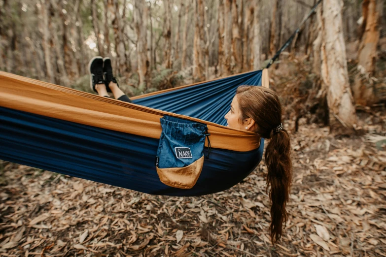 a girl sitting in a blue and brown hammock