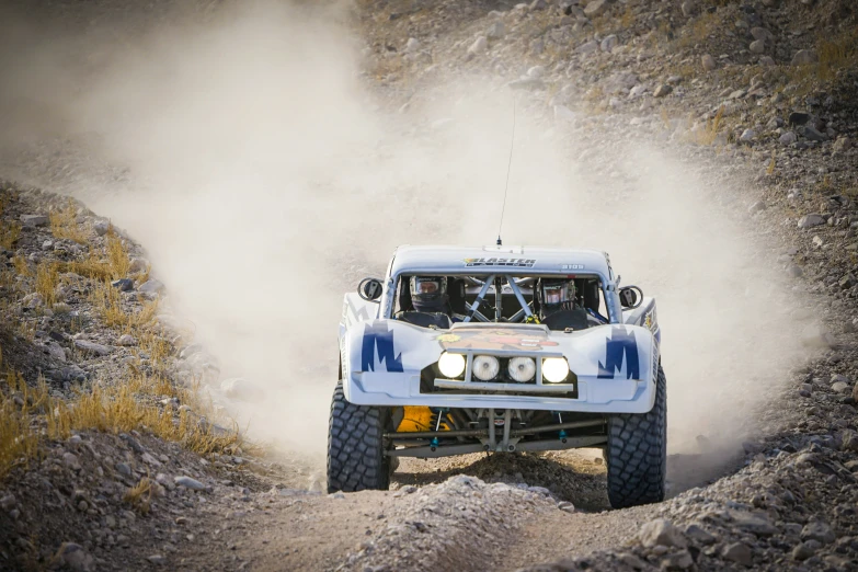 a blue truck going through the desert with smoke