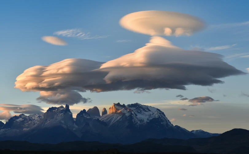 clouds hang above mountains with a clear blue sky