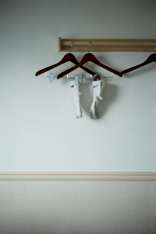 some coat hangers on the wall with clothes hanging from them