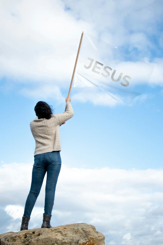 a woman holds up the jesus flag in the sky