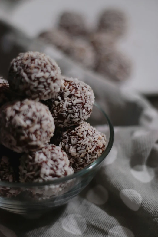 a bowl filled with coconut bliss balls on a table