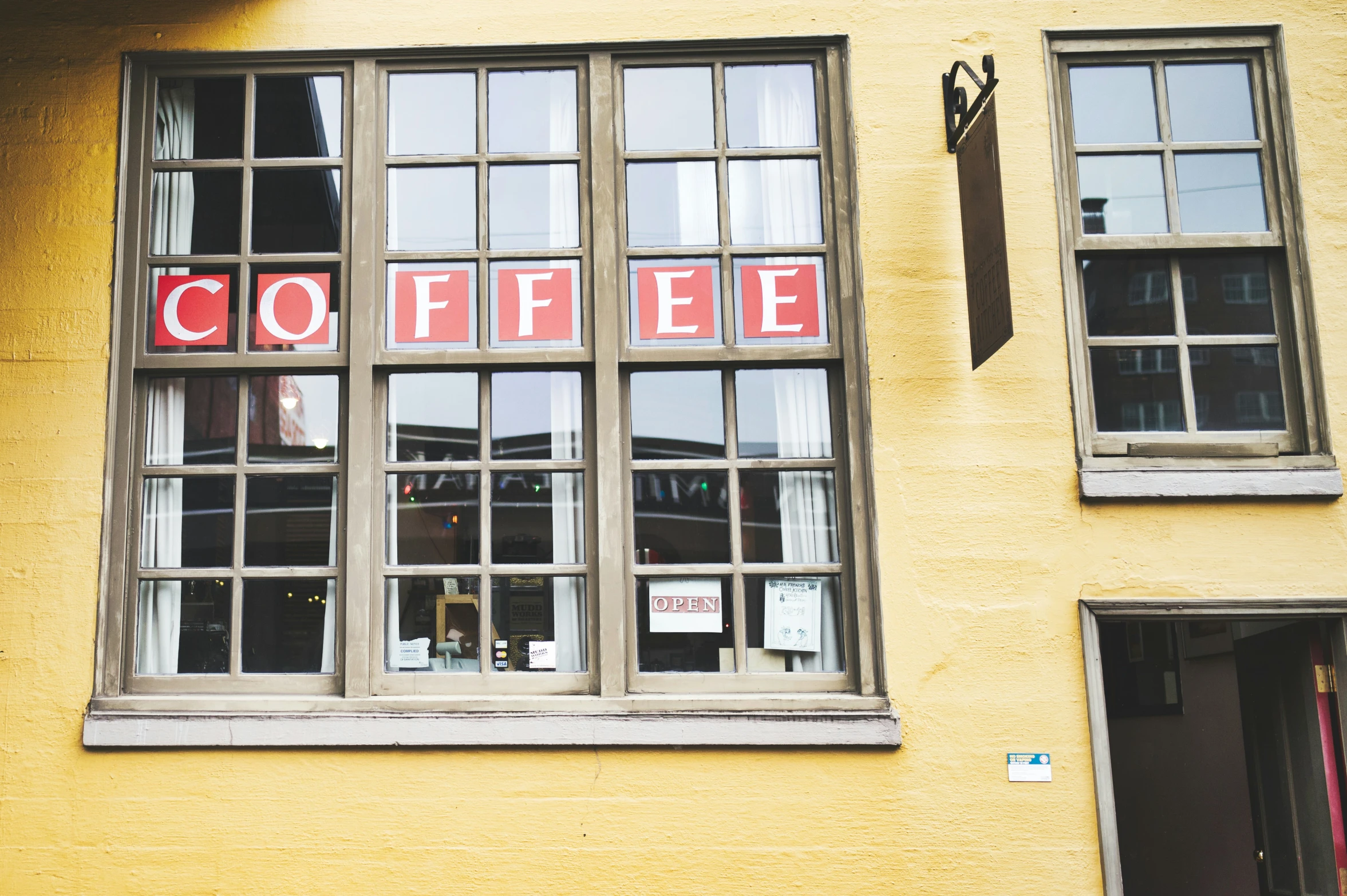 a yellow building with two windows that read coffee