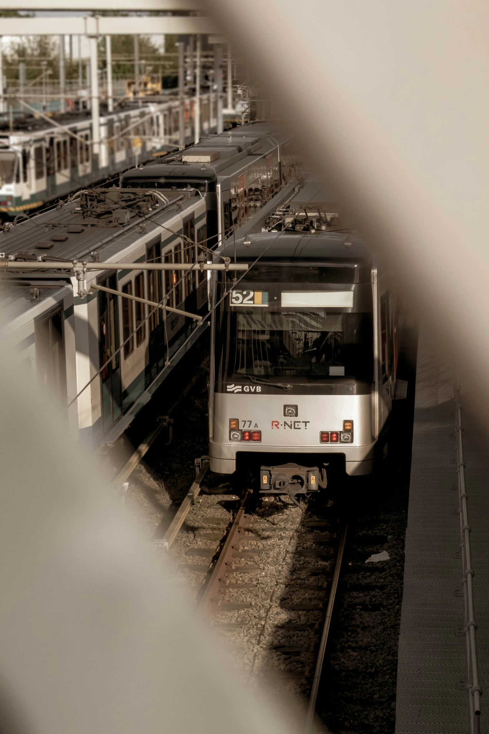 a silver train traveling on top of tracks near a station