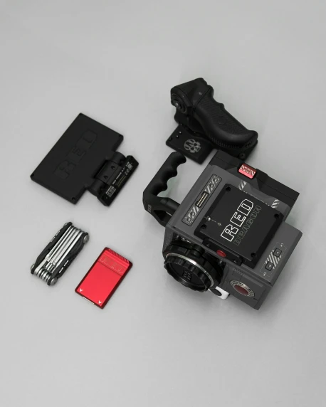 an analog po camera next to a battery and tools