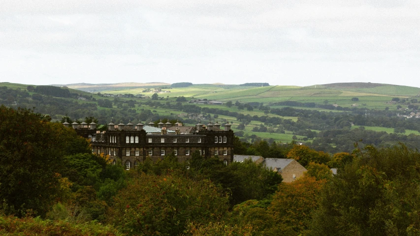 a building stands on top of the hill, overlooking a forest