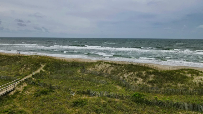 a grassy hill leading to the beach with a person on the other side