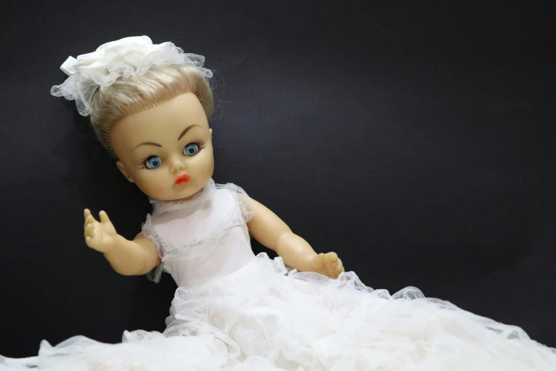 a little doll in white dress and a bow around its head