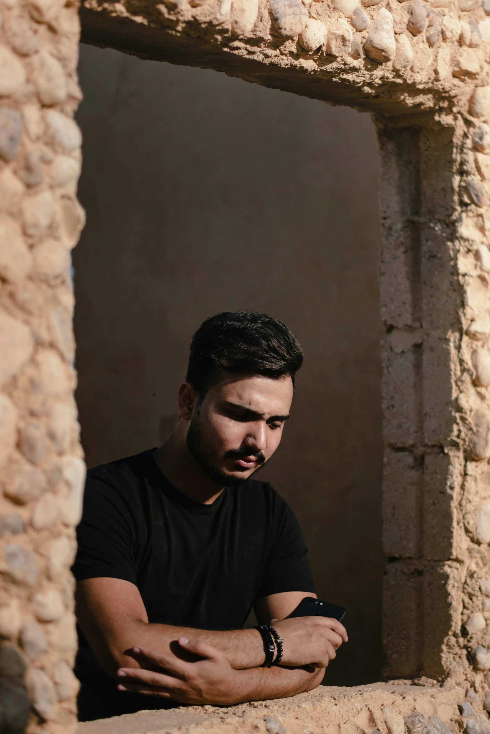 a man leaning on the edge of a stone building