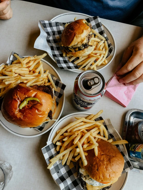 four hamburgers with french fries, a canned soda and a drink