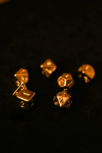 a black surface has five gold colored metal dices