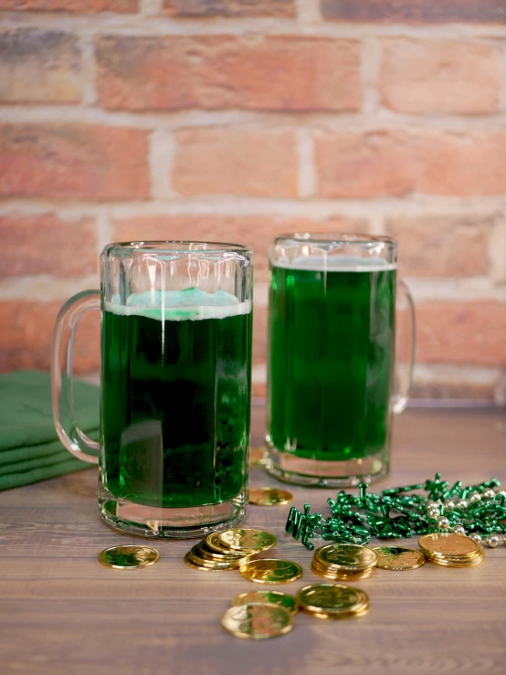 two beer mugs filled with green liquid and gold coins