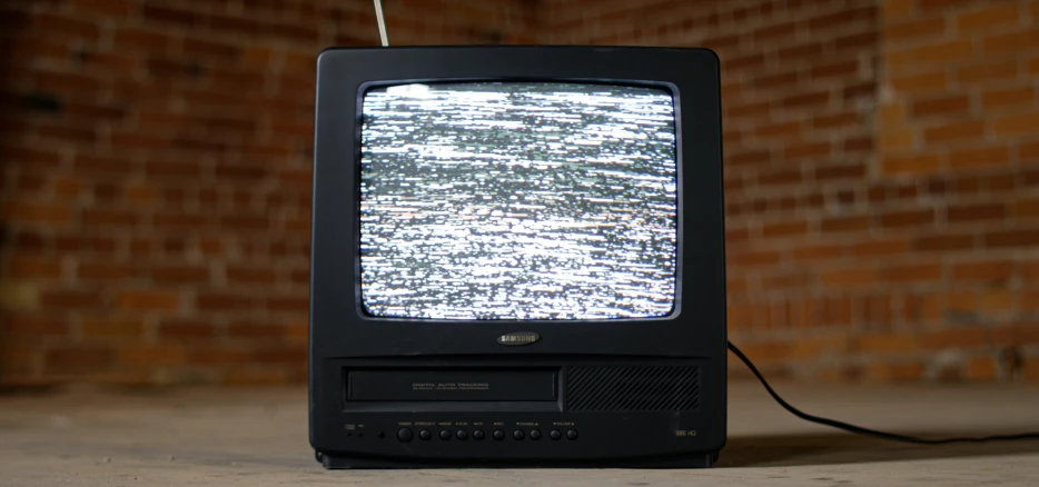old television sitting in front of a brick wall